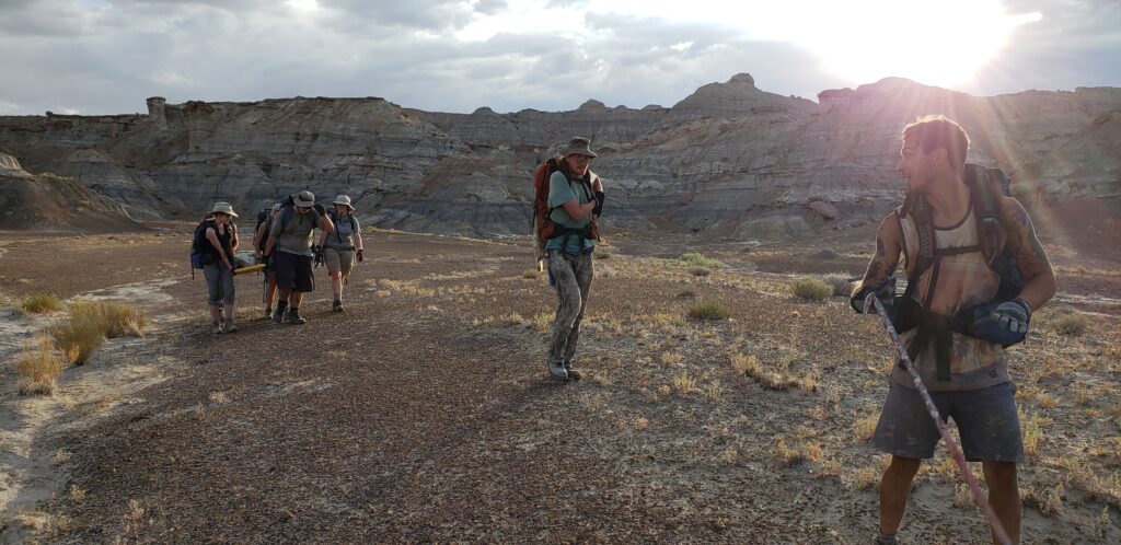 team of paleontologist carries dinosaur bones